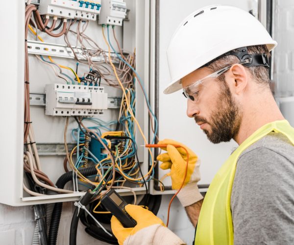 handsome-electrician-checking-electrical-box-with-multimetr-in-corridor.jpg